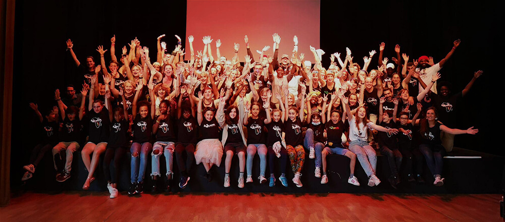 Photo de groupe de tous les élèves de l'association Soundiata enfants et adultes qui respire la joie, les mains en l'air